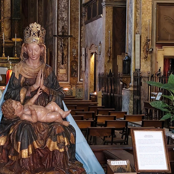 La Madonna con il Bambino da vicino; dietro, il crocifisso sulla parete e i banchi