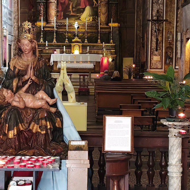 La Madonna con il Bambino, le mani giunte bianche, l'altare maggiore e il crocifisso; davanti la cassetta delle offerte