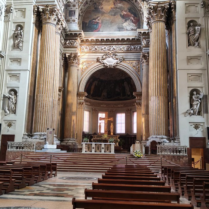 Il presbiterio della Cattedrale tra le grandi colonne: l'altare, il crocifisso e i fiori gialli e bianchi